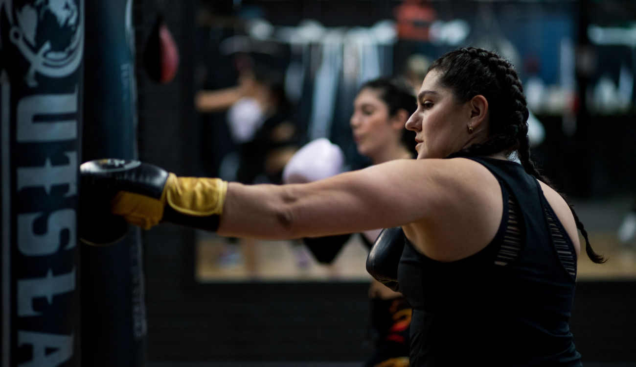 Girl wearing boxing gloves hitting a heavy bag